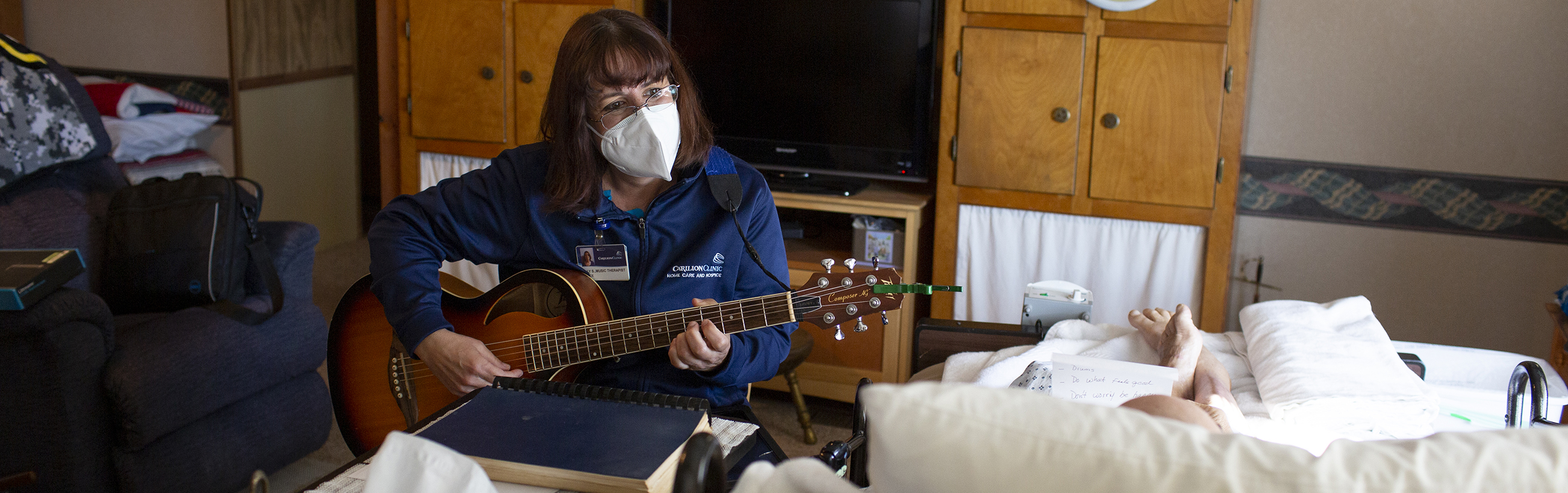 Kelly Sweeny playing a guitar while visiting with hospice patient