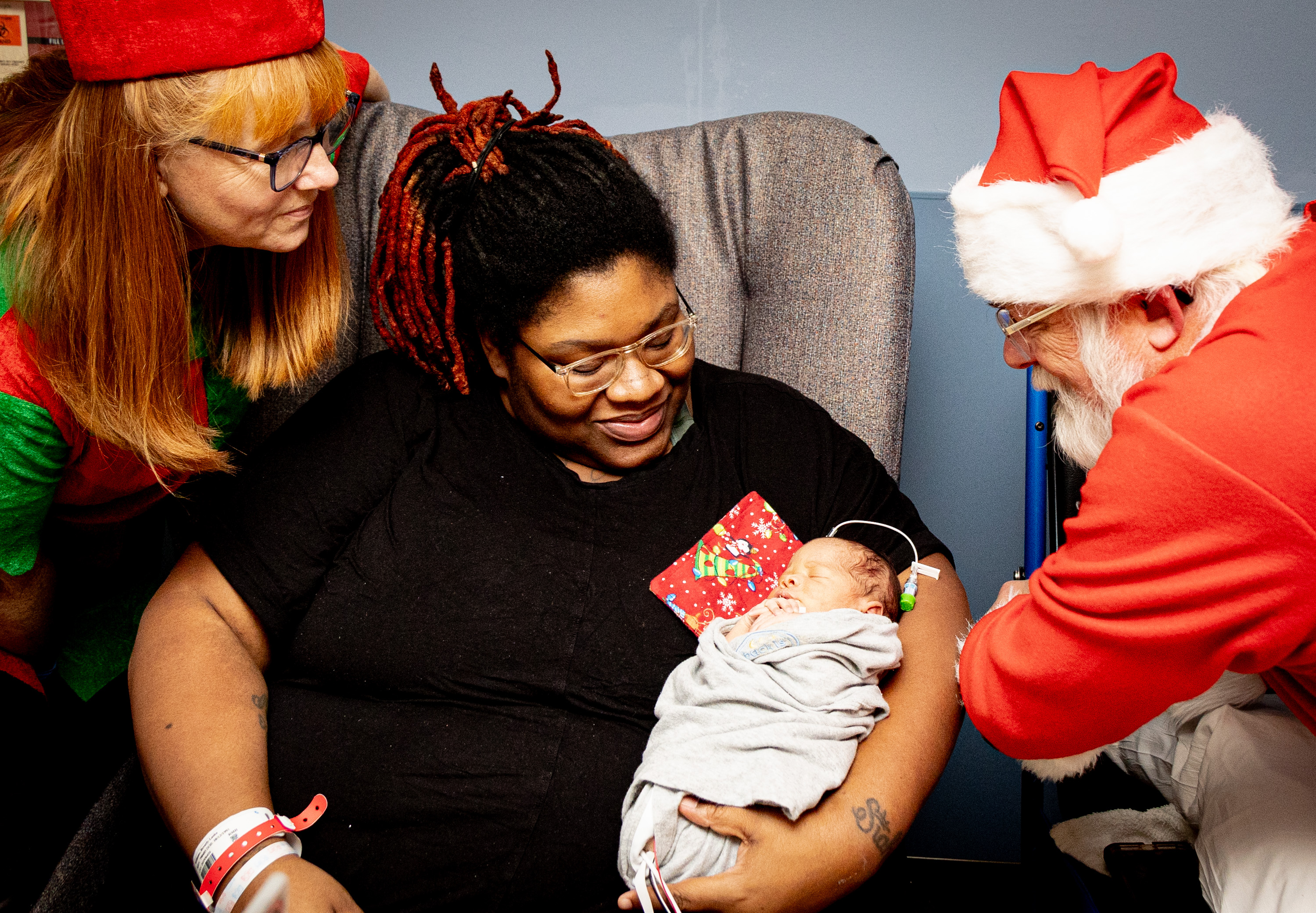 Santa and an elf visit with a NICU patient and their family.
