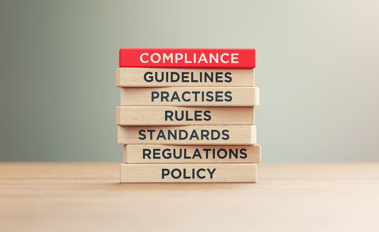 Words printed on wooden blocks that are related to compliance.