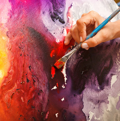 A closeup shot of a hand painting a canvas.
