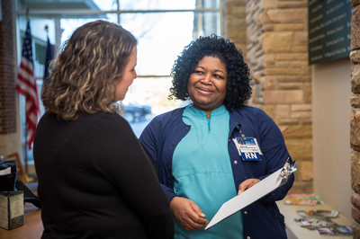 Two employees discussing information on a clipboard.