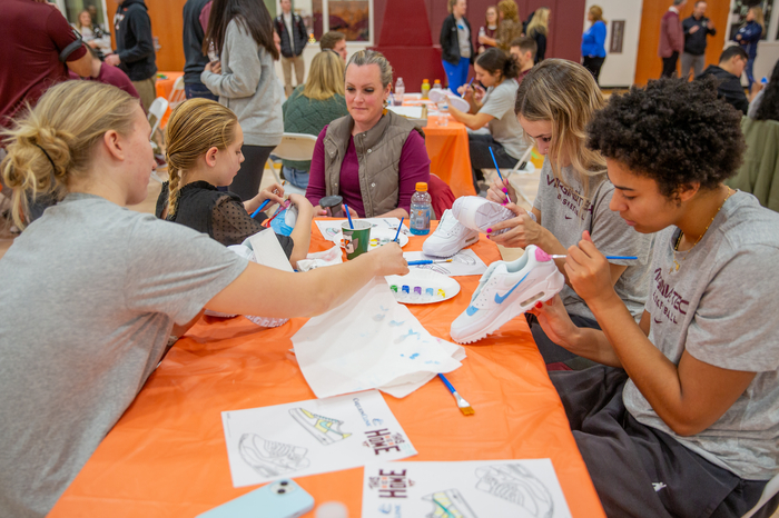 Virginia Tech's Women's Basketball players (left) Matilda Ekh and (right) Carleigh Wenzel and Carys Baker painting sneakers. 