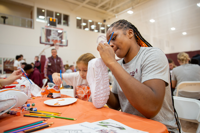 Virginia Tech's Women's Basketball player Rose Micheaux paints a plain sneaker.