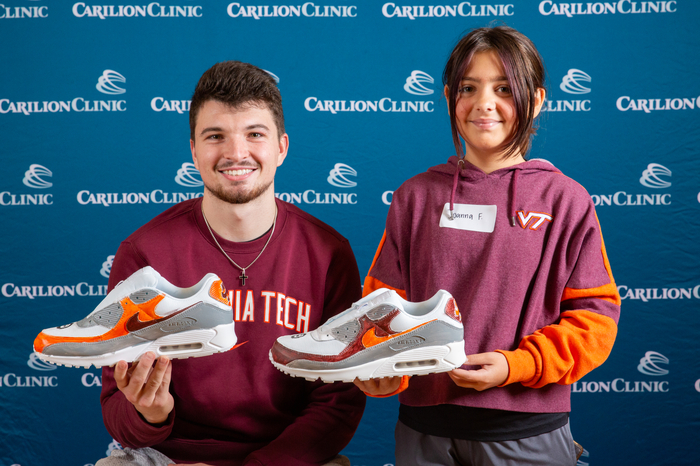 Virginia Tech Men's Basketball player Hunter Cattoor and his sneaker-painting partner pose with their pair of shoes.