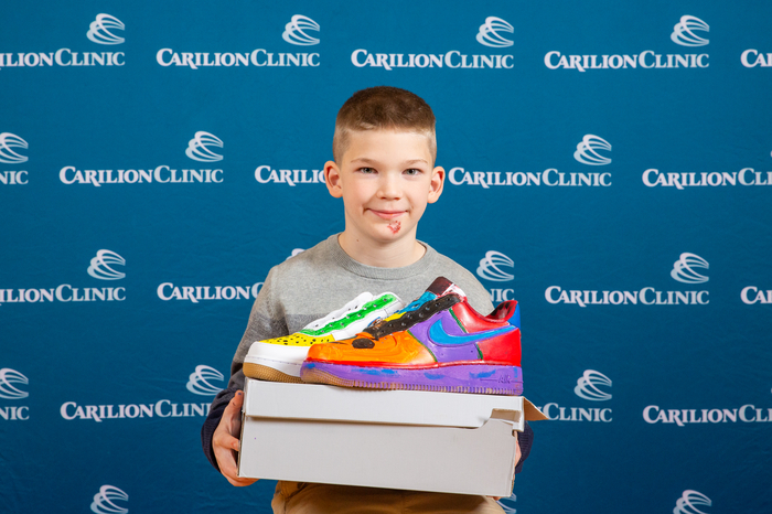 A pediatric patient poses with the shoes he designed.  