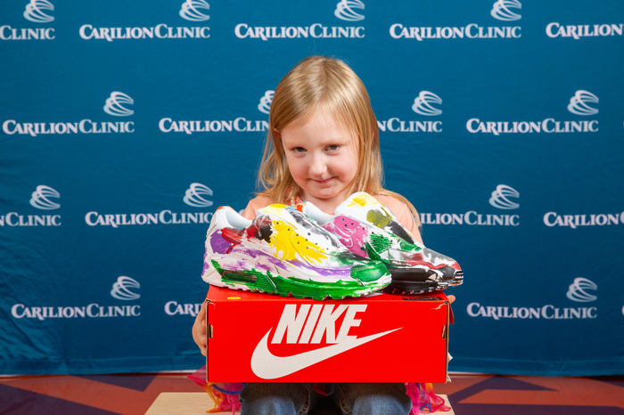 A pediatric patient poses with the sneakers she painted. 