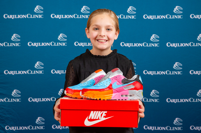 A pediatric patient holds the pair of sneakers she painted.
