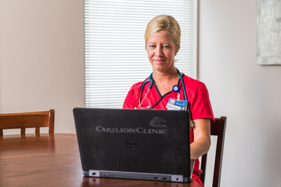 A nurse sitting in front of a laptop.