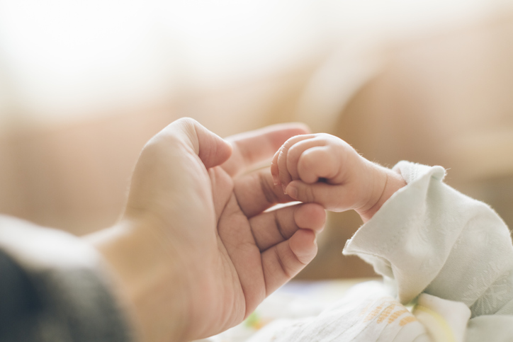 A mother holding a newborn baby's hand.