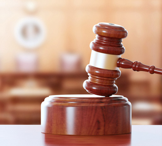 A gavel with a courtroom pictured in the background.
