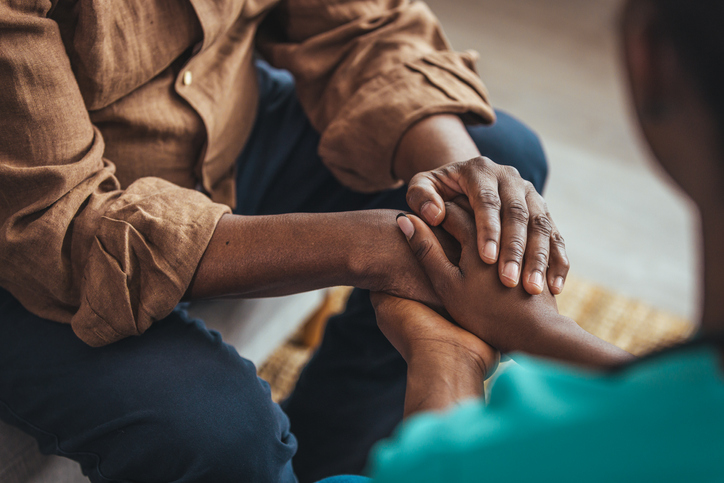 Two people holding hands, symbolizing support and care.