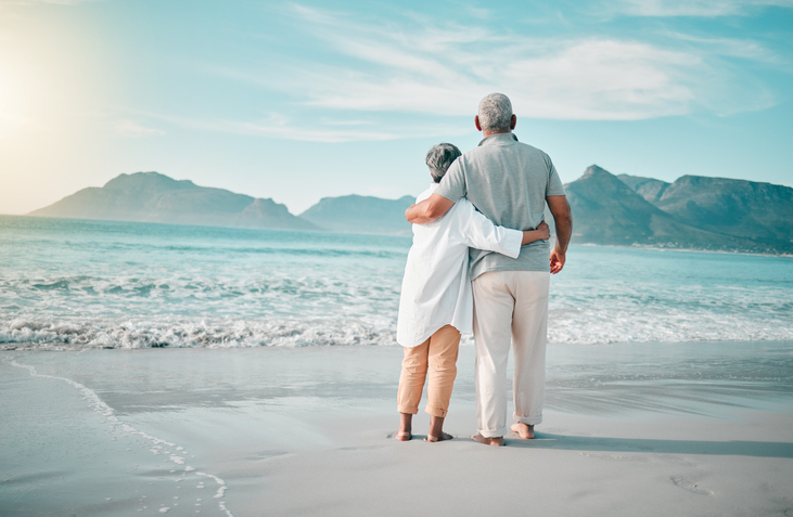 Two partners embracing on a beach.