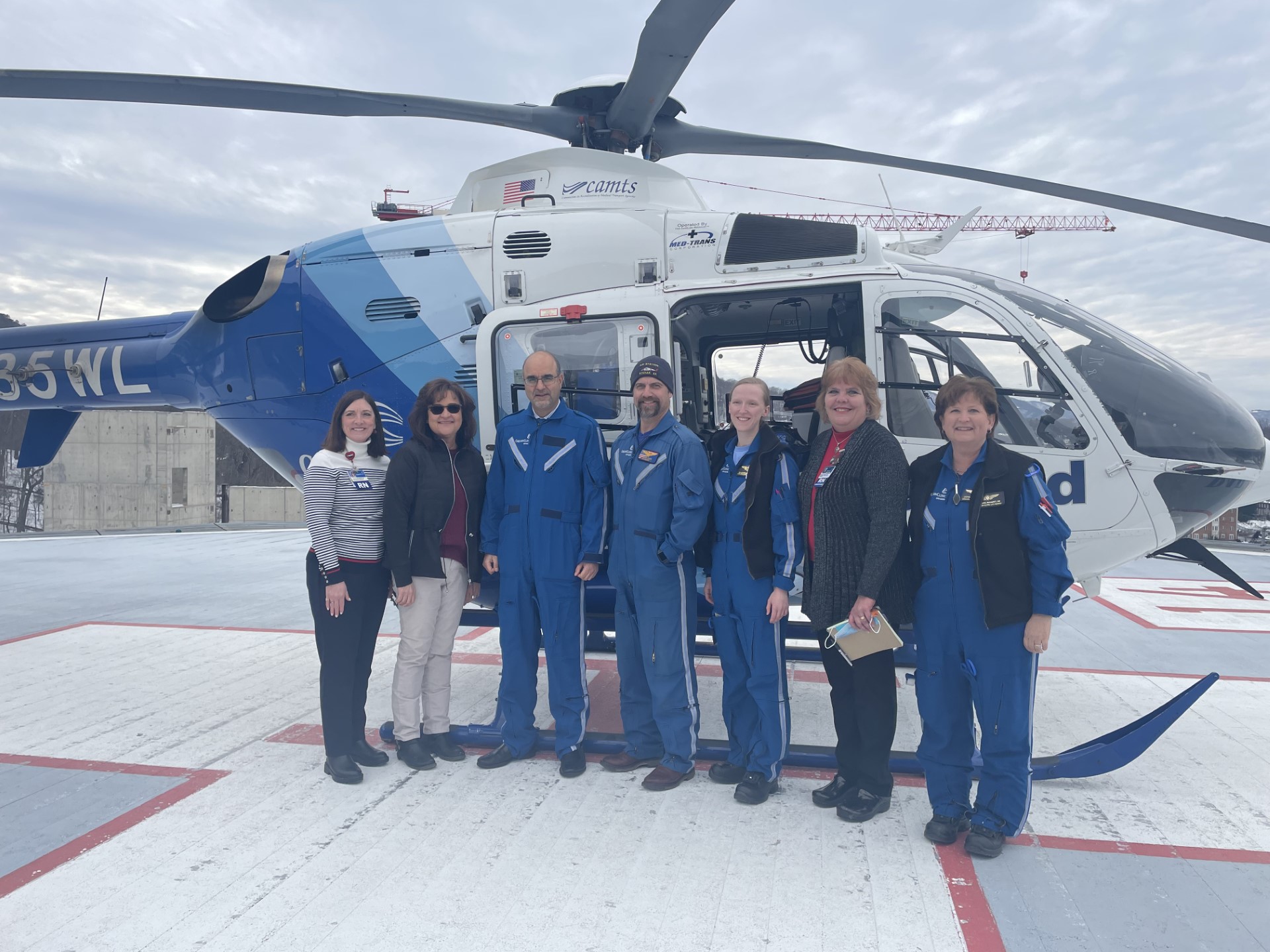 team posed outside of the helicopter before takeoff