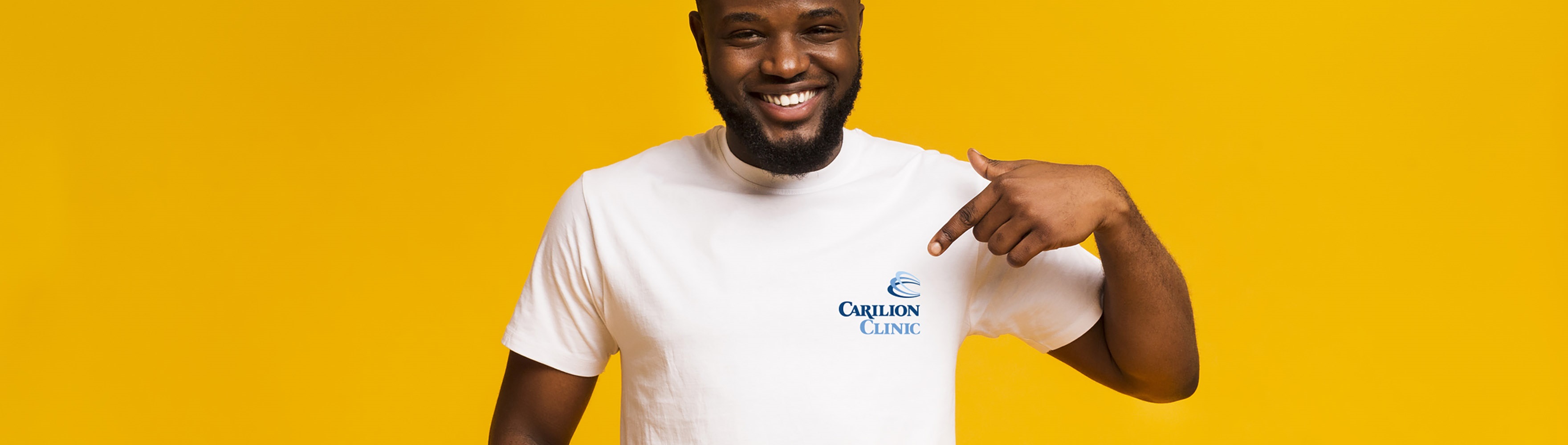 man wearing Carilion Clinic t-shirt on yellow background