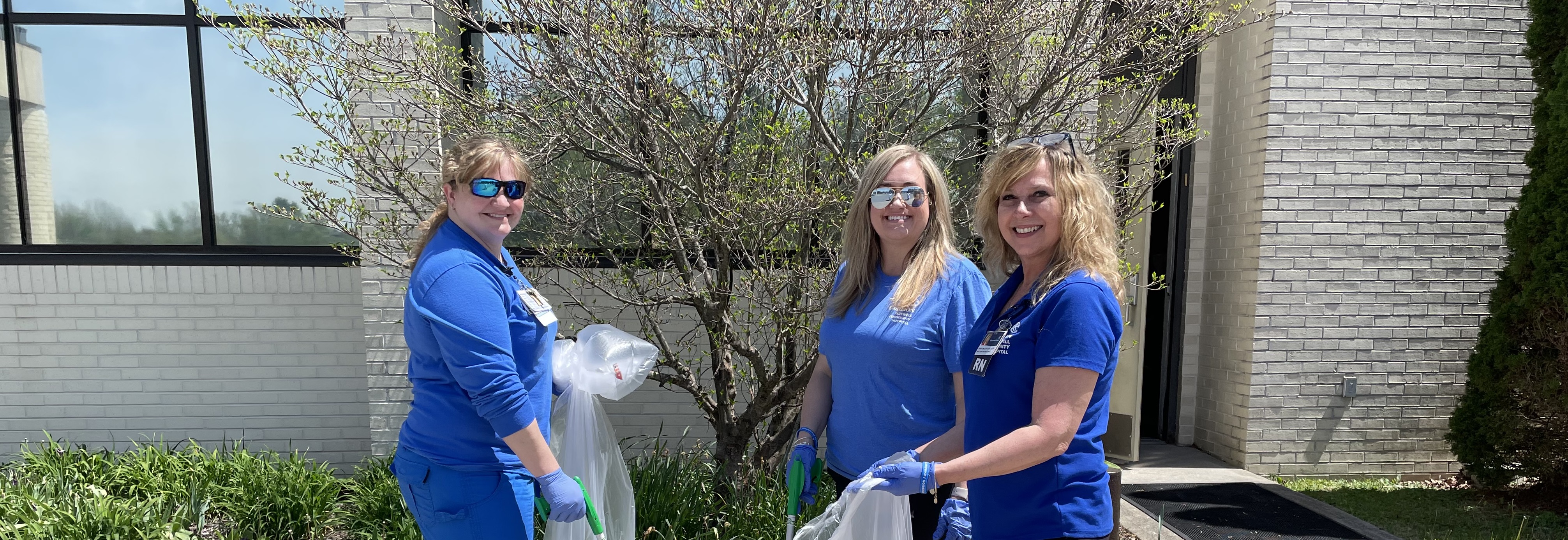 three Carilion Clinic employees cleaning up outside on Earth Day