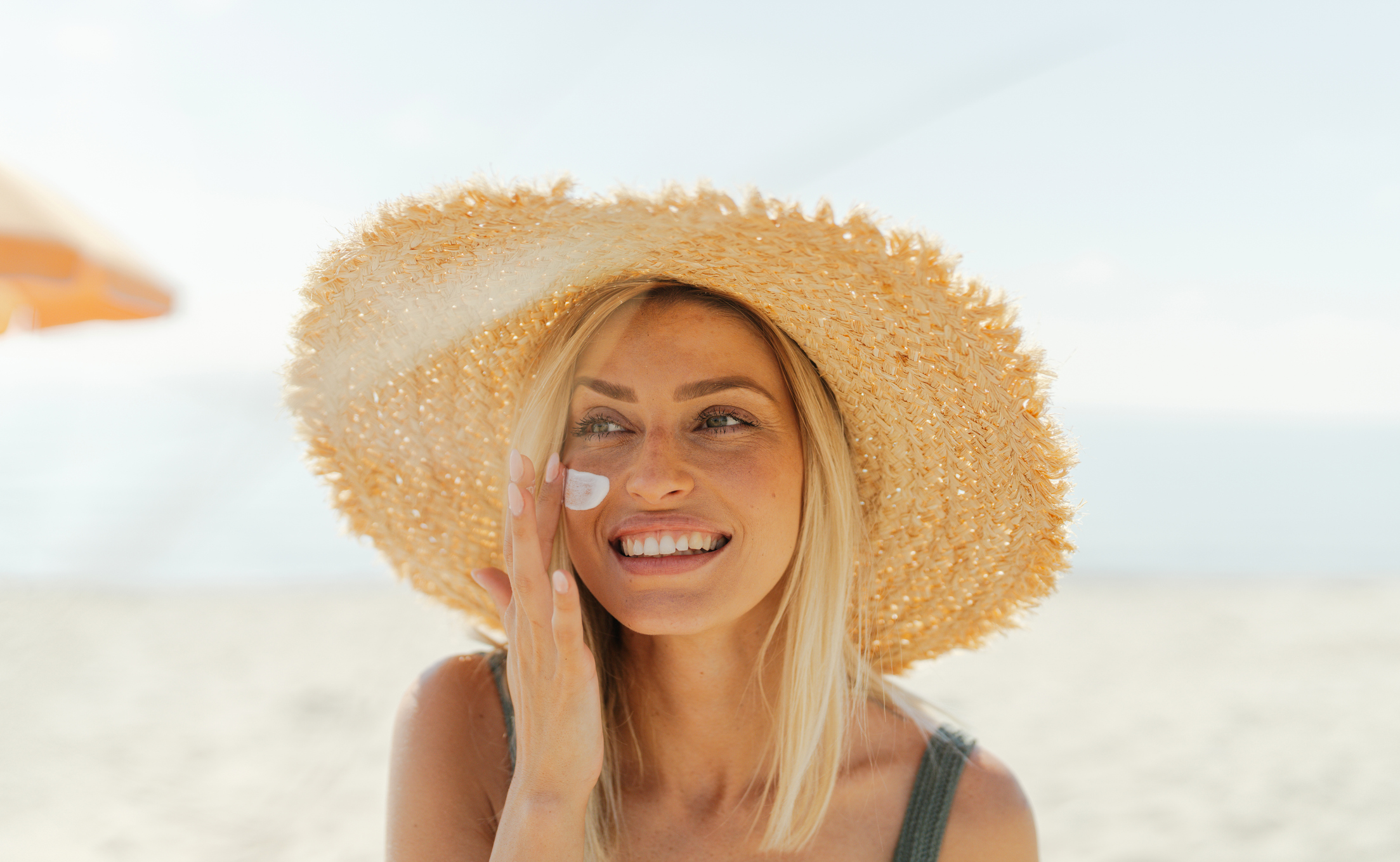 Woman applying sunscreen on face.