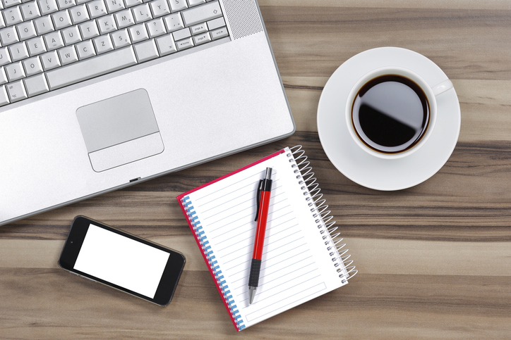 computer, phone, notebook and coffee on desk