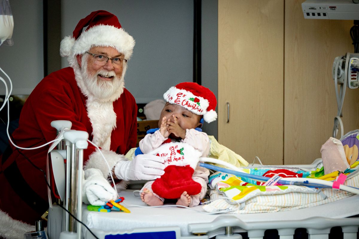 Santa poses with baby in Santa hat