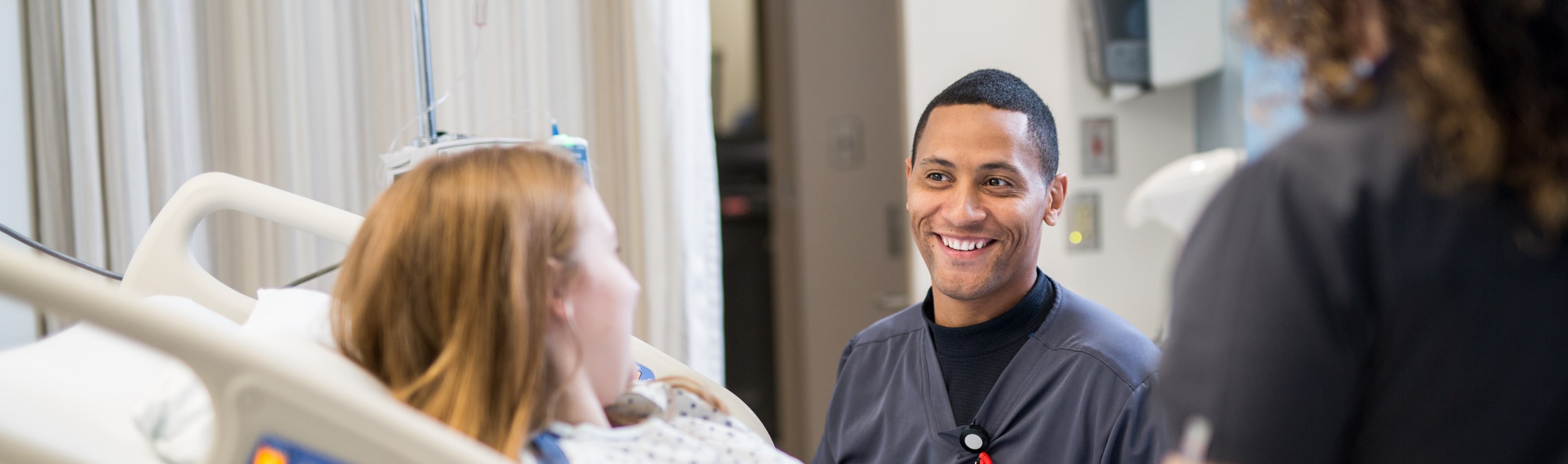 Nurses at a patient's bedside with smiles. 