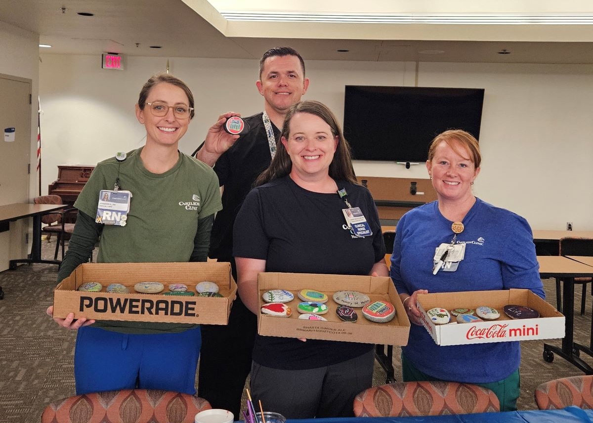 Team members display the rocks that were painted at the event.
