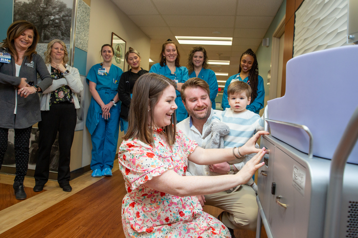 Carilion nurse Megan Foster affixes a small plate to the cooling bassinet she and her husband, Mac, helped purchase in memory of their daughter, Poppy, for Carilion Roanoke Memorial Hospital’s Labor and Delivery unit. They are pictured here with their 2-year-old son, Lincoln.