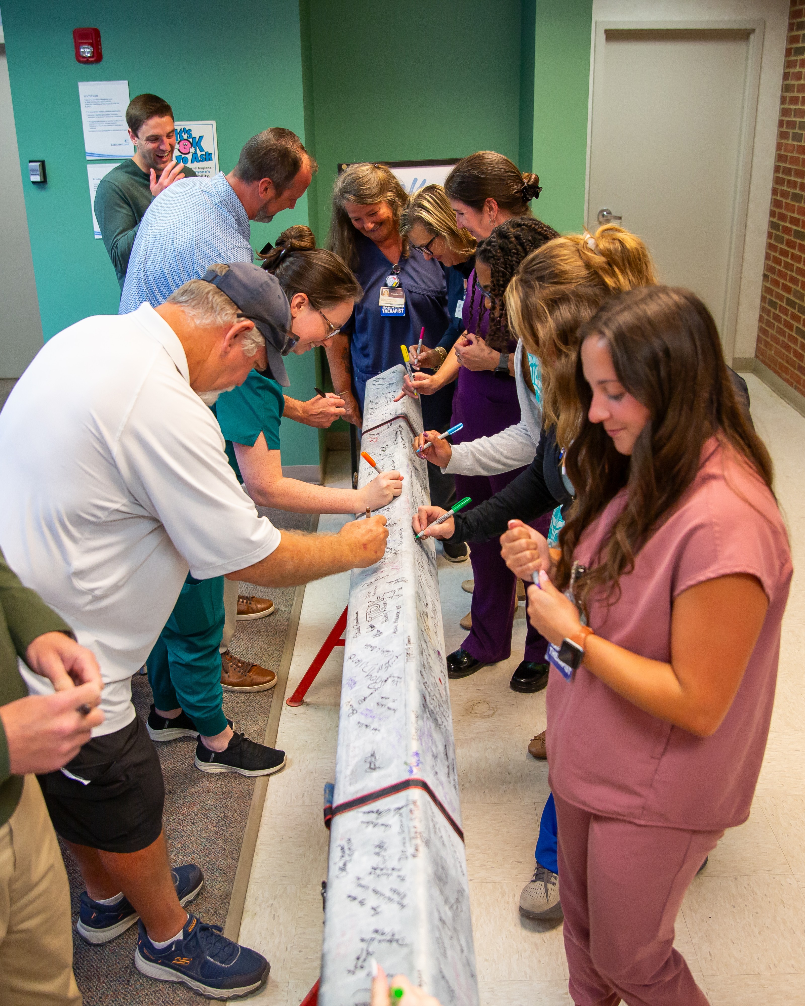 Team members sign the beam.