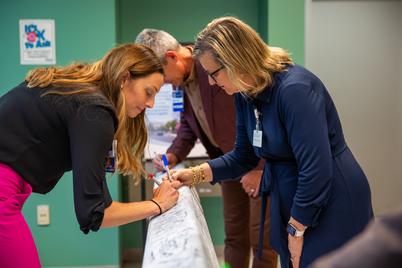 Team members sign the beam.