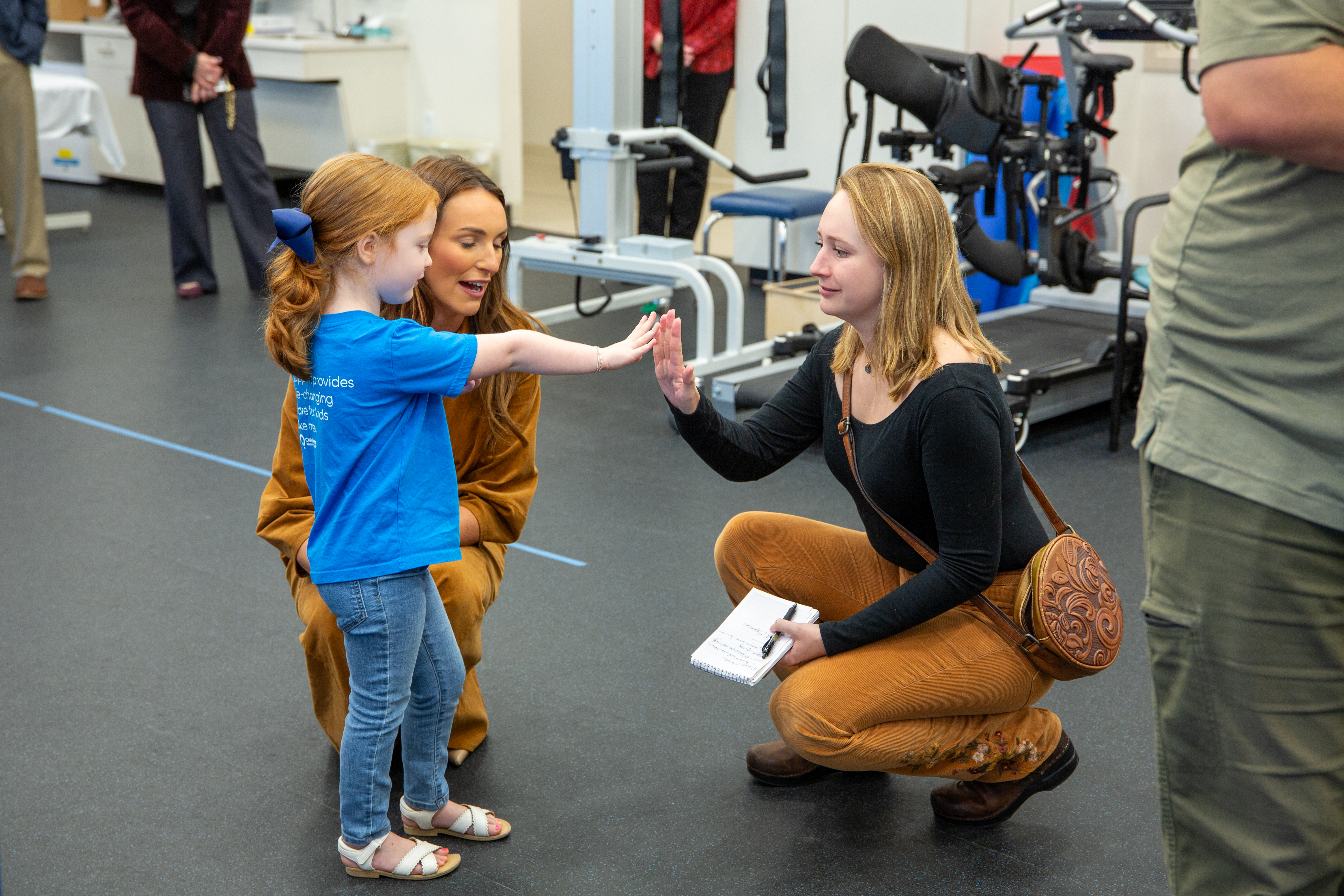 CMN Champion Madi Spencer giving a journalist a high-five in the therapy gym