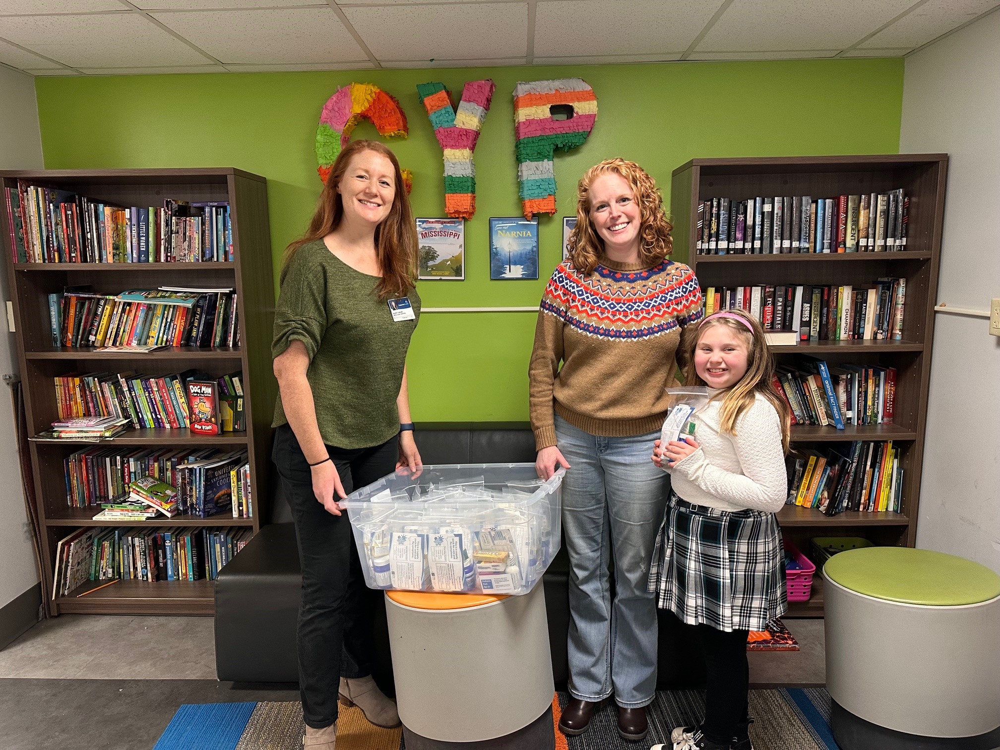 photo of Mandy Swann, Jackie Smith, and a child receiving cold relief packs for after school program families