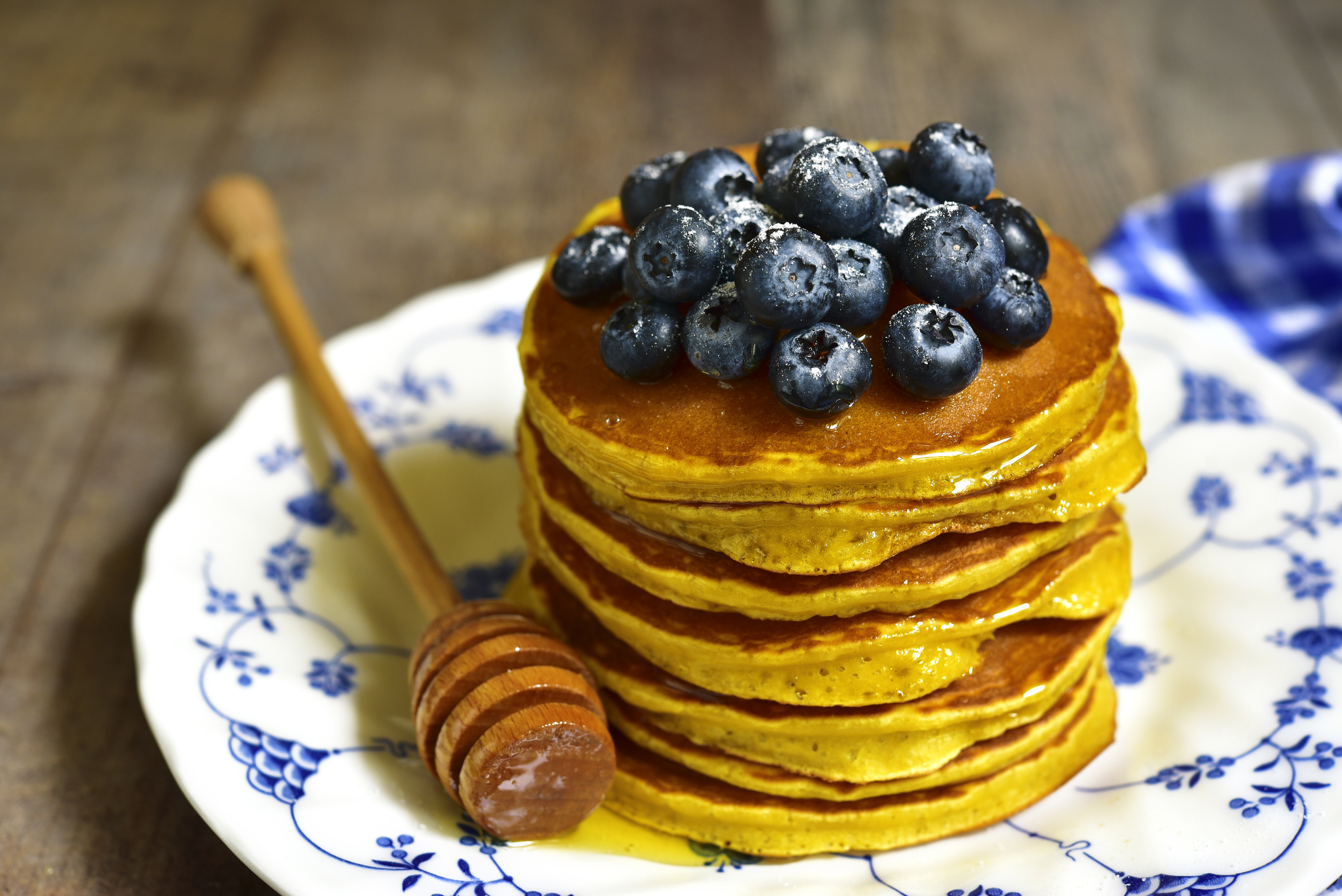A stack of pumpkin panckakes served with berries and honey.