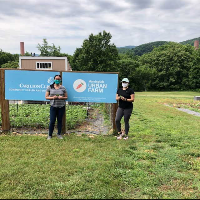 Graduate students pose in front of Morningside Urban Farm sign