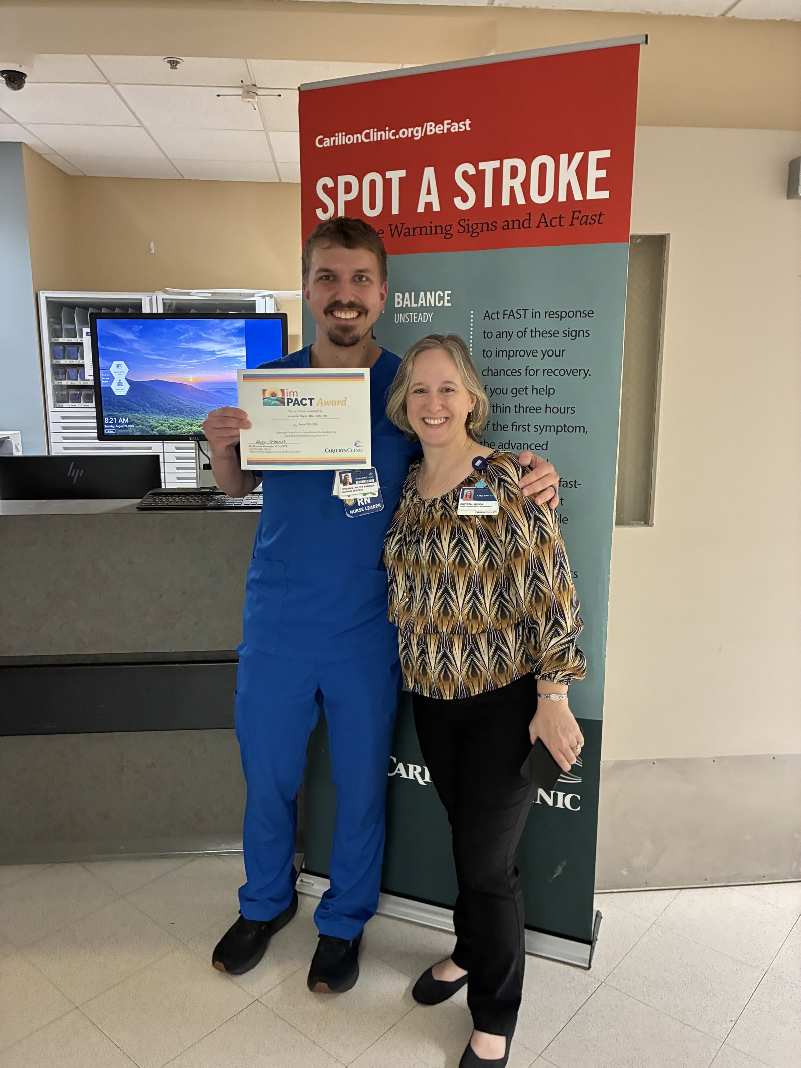 Jordan holding the award certificate with a colleague