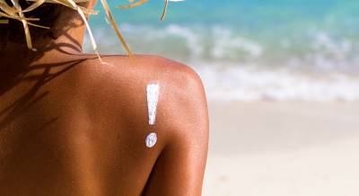 Woman at beach with an exclamation point written in sunscreen on her back