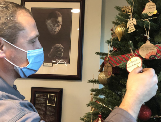 Electrician Nick Aesy adjusts an ornament on the Lights of Love tree. He and two co-workers decorated the CRMH lobby.