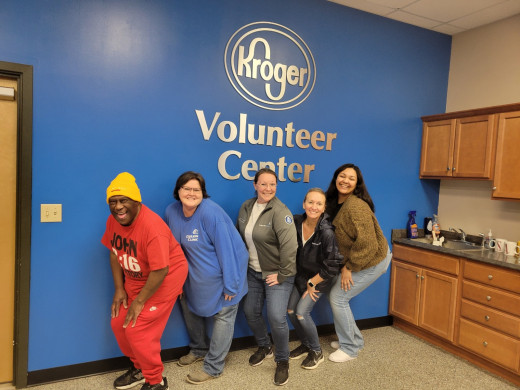 From left to right: James Andrews, Sherry Hartsel, Jennifer Evans, Leslie Wyatt, and Cara Basham posing in from of the Kroger Volunteer Center sign