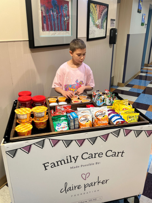 A pediatric oncology patient is looking at the Family Care Cart and deciding which snack to select. 