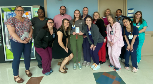 Peyton Smith RN (center with award) with Nursing Center of Excellence team members and 10MPCU team members 