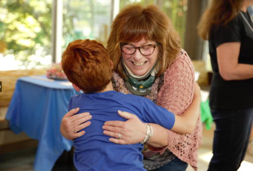 Dr. Atkinson hugging and smiling young patient 