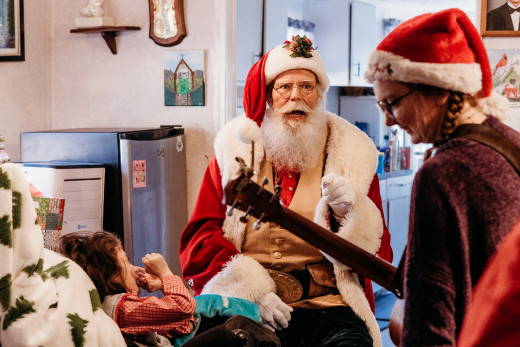 Santa and Hospice Music Therapist Jessie Palmer visit with a pediatric hospice patient