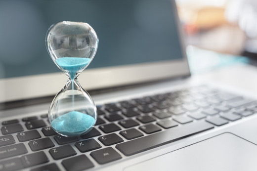 stock image of hourglass with laptop in background indicating looming deadline