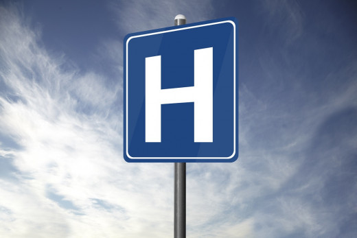 stock image of hospital sign against partly cloudy sky
