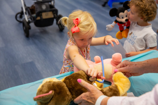 A girl listening to her stuffed animal's heart with a stethoscope. 