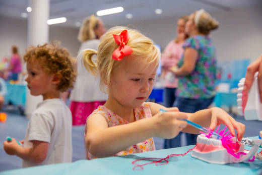 A girl learning about cleaning teeth with an interactive game and brushing demo.
