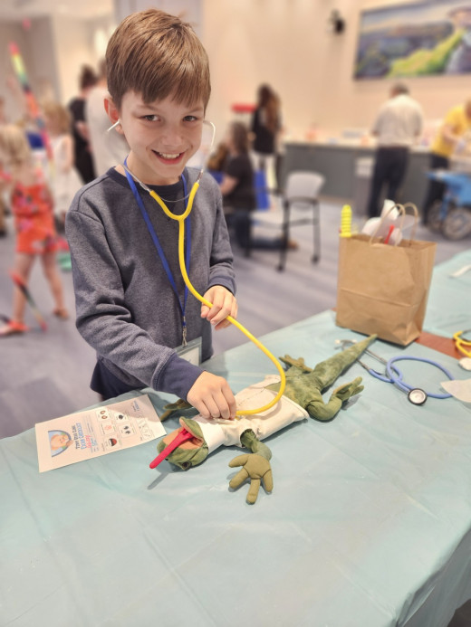 A boy helping his stuffed lizard get through our triage station. 