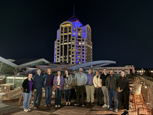 The ID and Stewardship team gathered in front of the Wells Fargo Tower as it glows purple for Antibiotic Awareness Week 2025