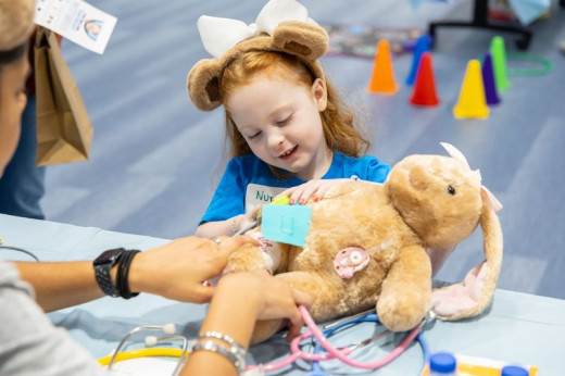 A young girl checking her stuffed bunny's blood pressure. 