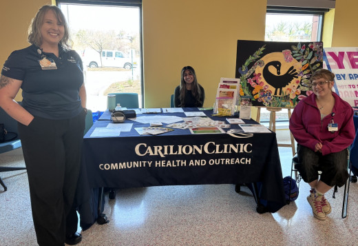 Pictured is a table with educational materials and three staff members.