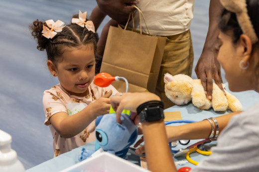A young girl focused on checking her stuffed animals vital signs. 