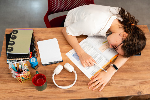 girl resting head on desk with homework