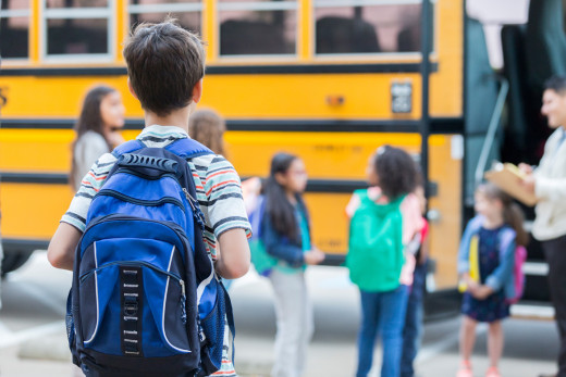 boy approaching school bus with students in line